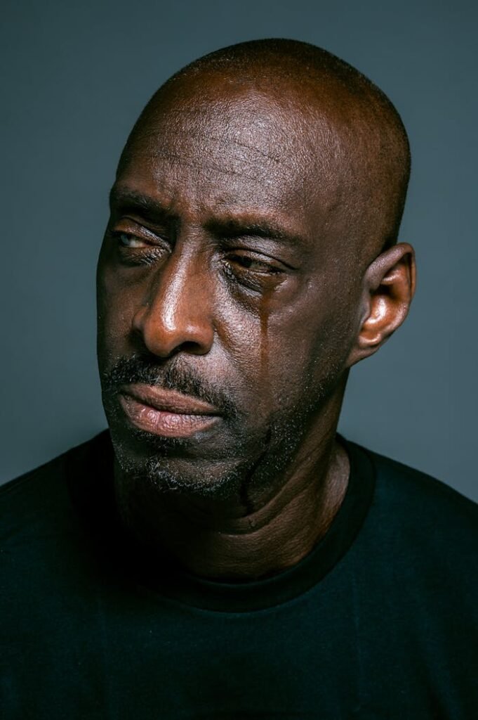 Close-up portrait of a serious bald man with teardrop, depicting deep emotion and thoughtfulness.